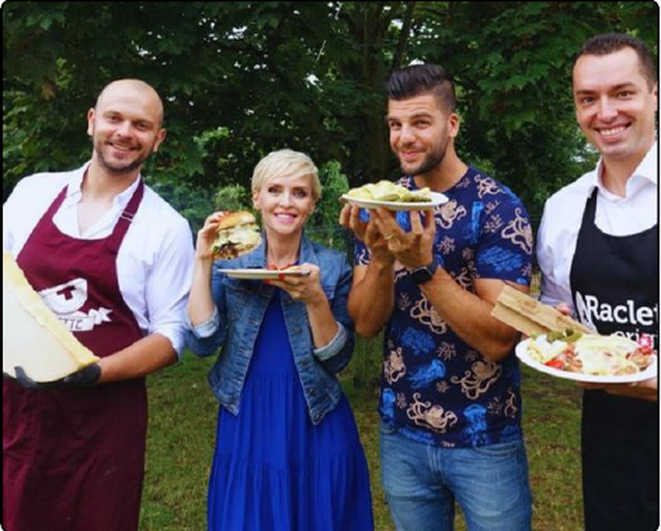 Skupina s Milanom Kolářom a hosťami s taniermi raclette a burgermi vonku