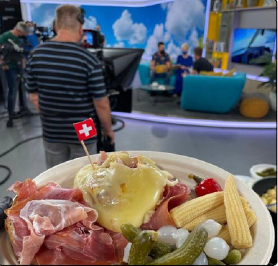 Tanier raclette so švajčiarskou vlajkou v televíznom štúdiu